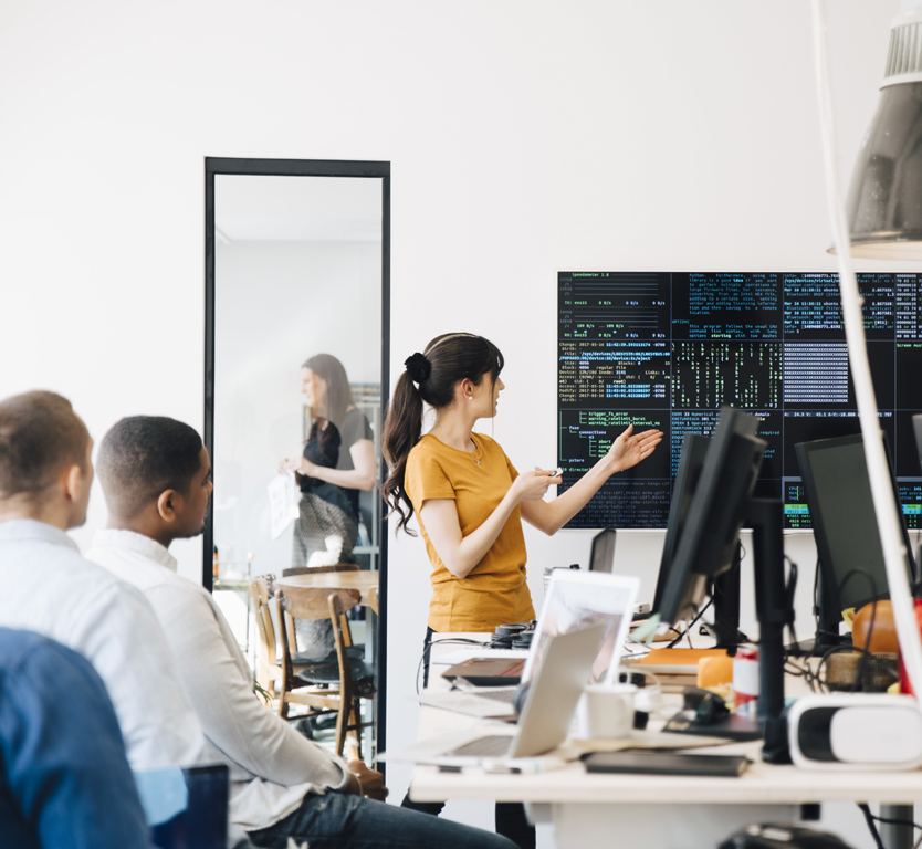 A woman presenting at a group of people and engaging in public speaking.