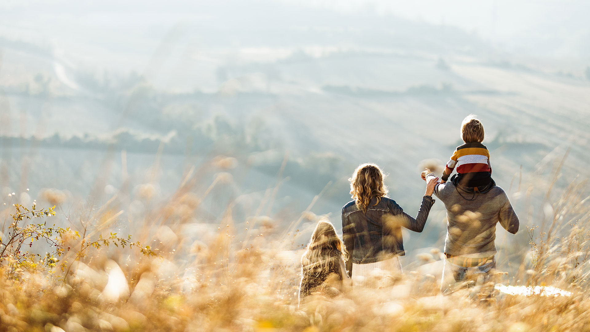 Familie in einem Feld mit Hügeln im Hintergrund