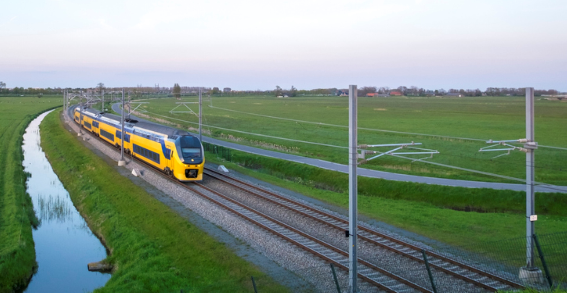 Een trein rijdt door het Nederlandse landschap over de rails. 