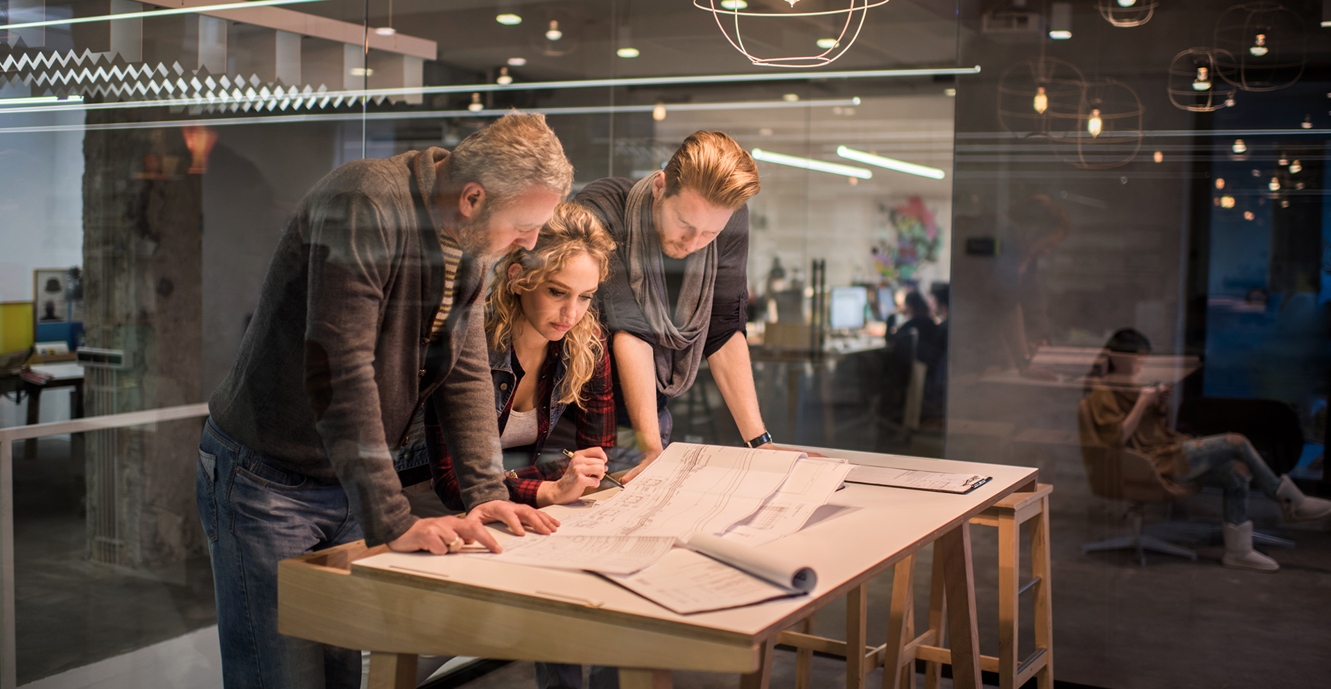Team van Arcadis Architecten gebogen over een tafel kijkend naar een ontwerp.