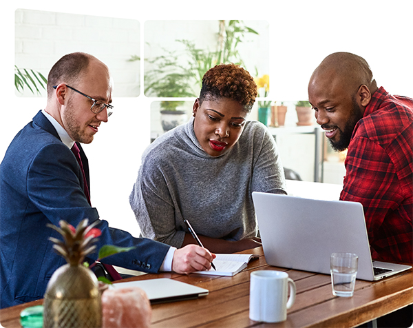 Three individuals seated at a table, engaged with a laptop, collaborating on a project or discussion.