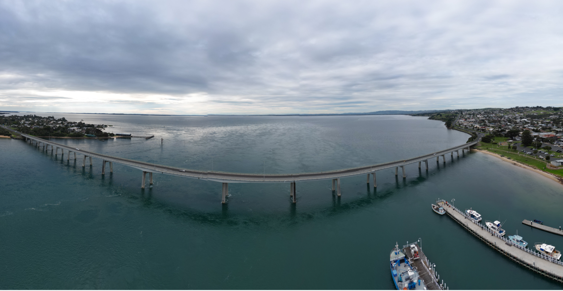 A bridge over water with distant boats.