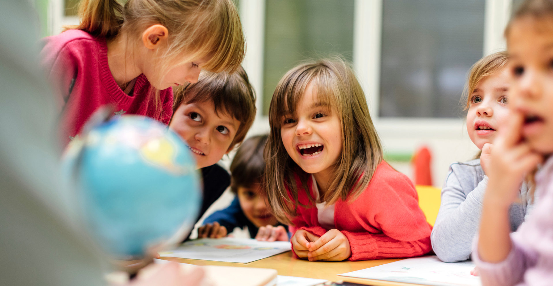 Kinderen die op school kijken naar een wereldbol.