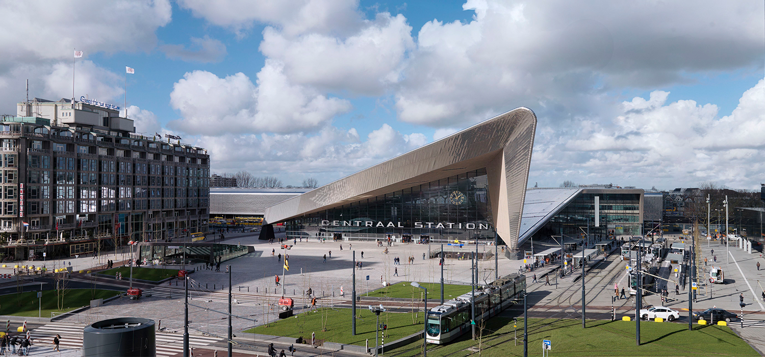 Stationsgebied met trams en plein en reizigers die van en naar Centraal station Rotterdam gaan en komen